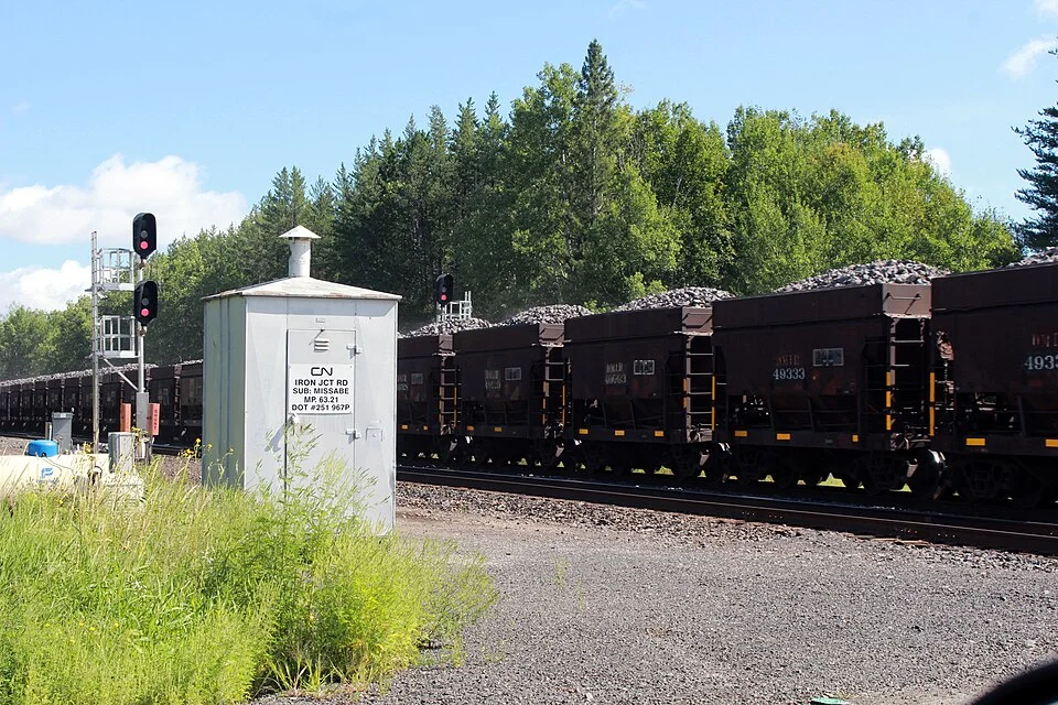 Iron ore transported in ore cars at Iron Junction, Minnesota: a comparative example of bulk mineral transport.