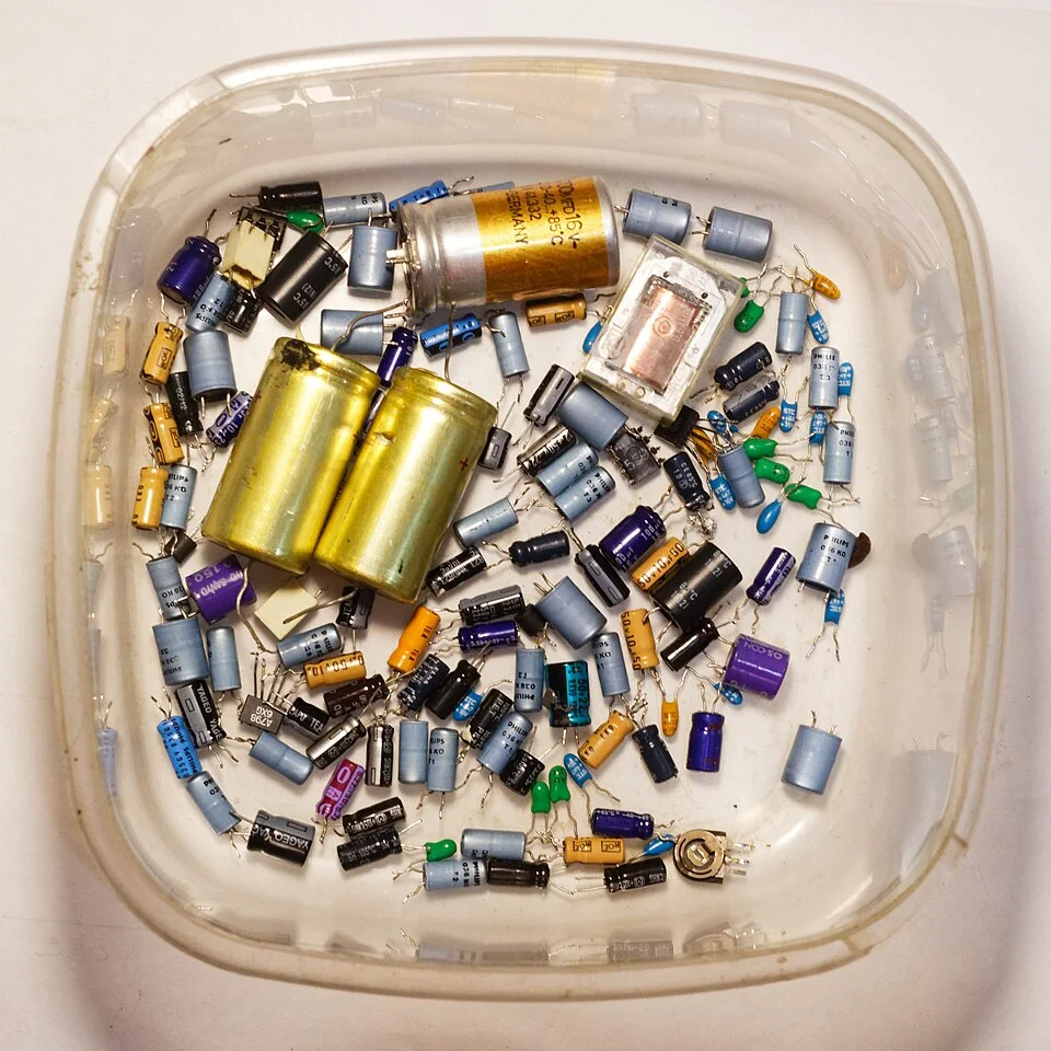 Discarded capacitors and other components from a Revox B215 cassette deck, illustrating component-level e-waste.